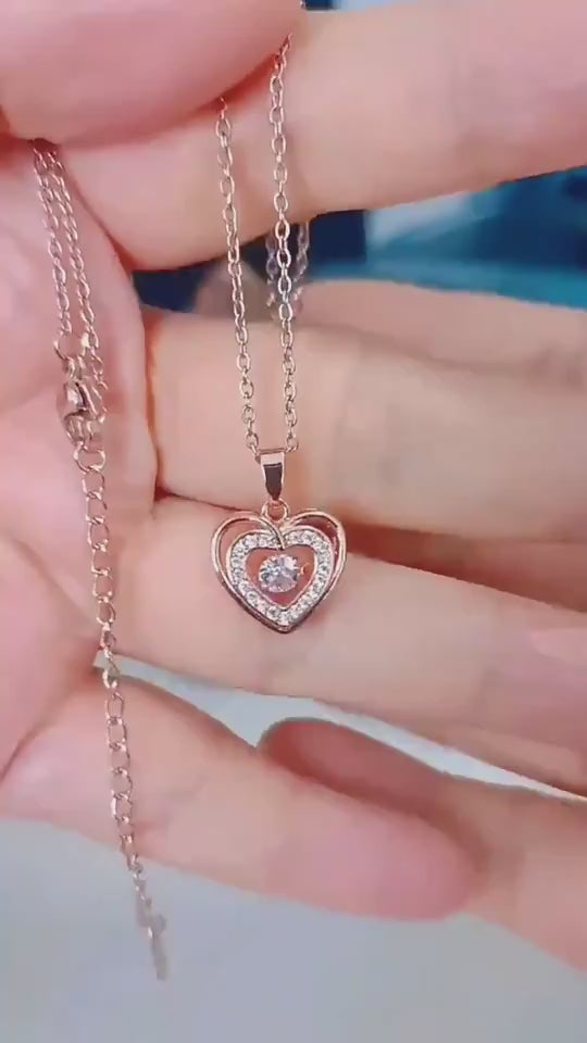 Gold heart-shaped necklace with a pendant on a gray surface 2