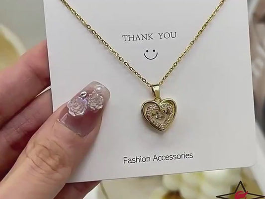 Gold heart-shaped necklace with a pendant on a gray surface video