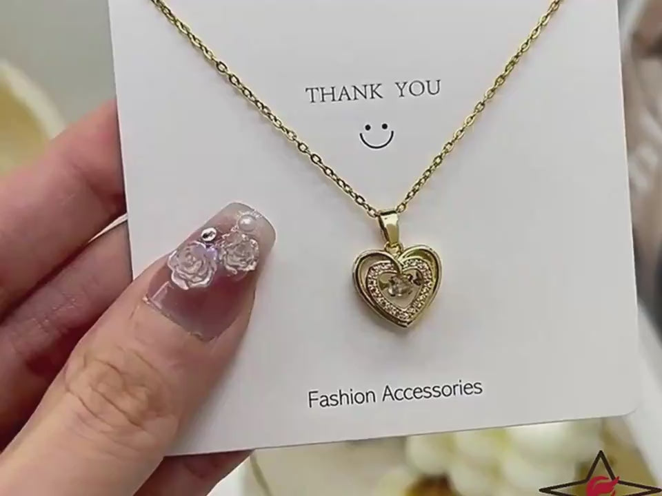 Gold heart-shaped necklace with a pendant on a gray surface video